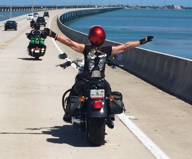 Martine, les bras levés sur sa moto